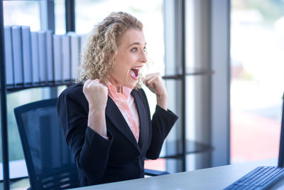 Mid adult woman looking away while standing on table at home