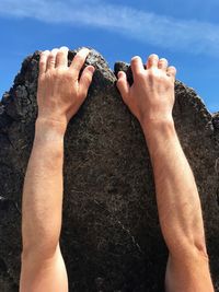 Cropped hands climbing on rock