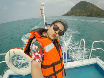 Portrait of young woman wearing sunglasses while puckering on boat in sea