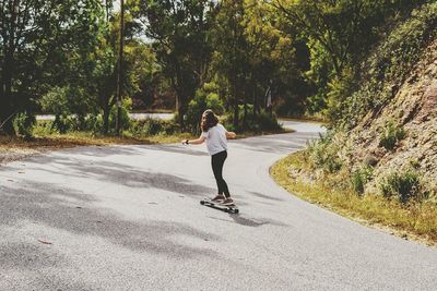 Full length of woman skateboarding on road