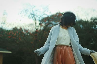 Rear view of woman standing against trees
