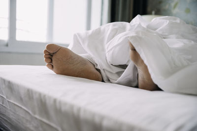 Low section of man lying on bed