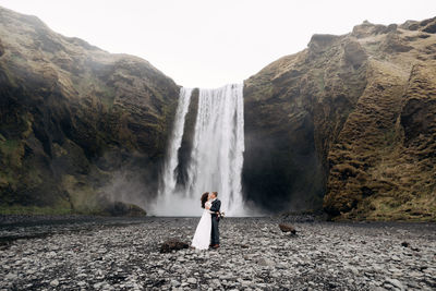 Man standing on rock against waterfall
