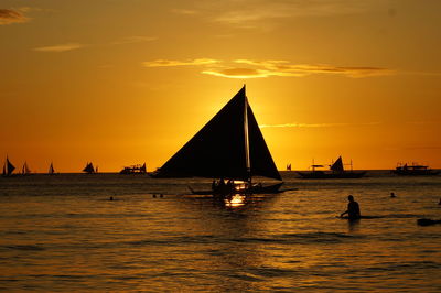 Silhouette sailboat sailing on sea against sky during sunset