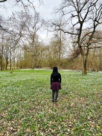 Rear view of woman walking on field