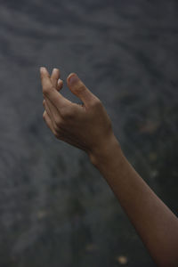 Close-up of person hand against water