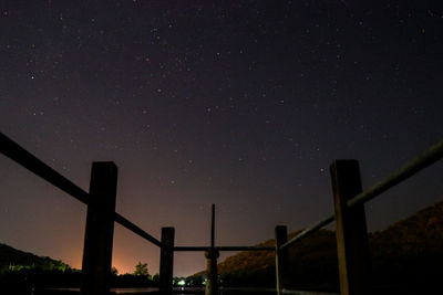 Low angle view of silhouette fence against clear sky at night