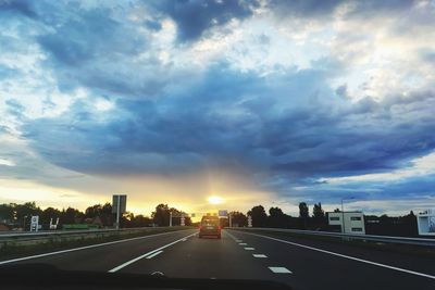 Road by city against sky during sunset