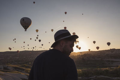 Man with hot air balloons against sky during sunset