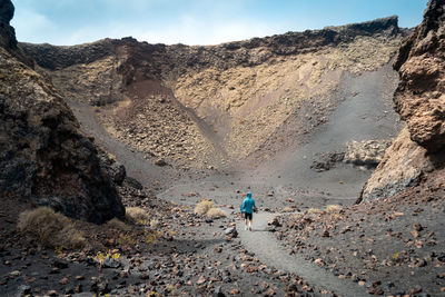 Rear view of man walking on land against sky