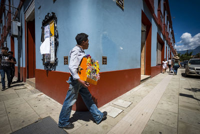 Full length of man walking on footpath in city