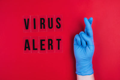 Virus alert on a red background and a gloved hand.