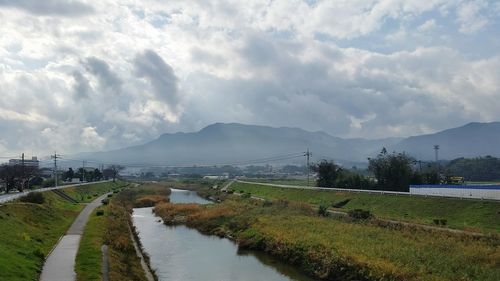 Scenic view of field by lake against sky