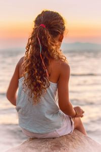 Girl looking at sea during sunset