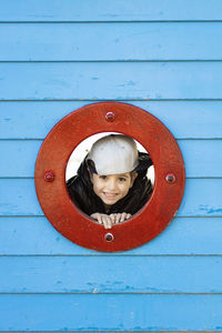 Portrait of smiling boy looking through circle shaped window