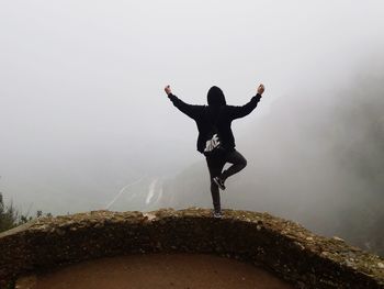 Man jumping on mountain against sky