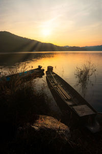 Abandoned boat at lake against sky during sunset