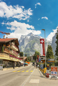 Road by buildings in city against sky