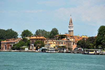 View of buildings by canal against sky in city
