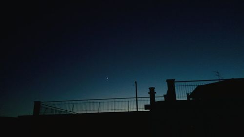 Silhouette fence against clear sky at night