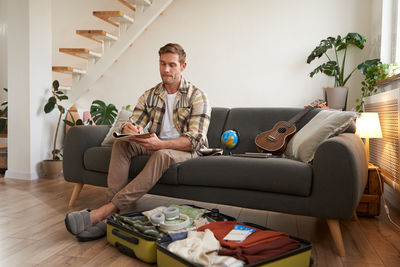 Young woman using phone while sitting on sofa at home