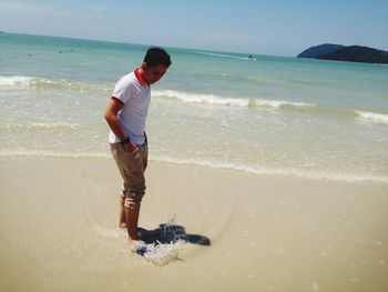 Man standing in sea against clear sky during sunny day