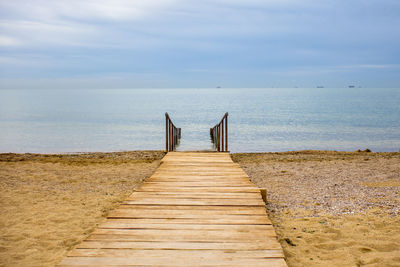 Wooden pier on sea shore against sky