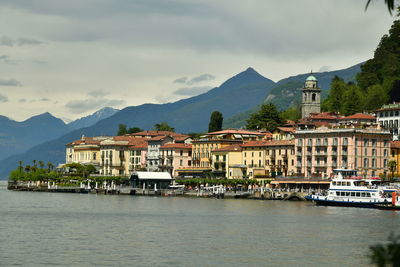 Buildings by lake against sky