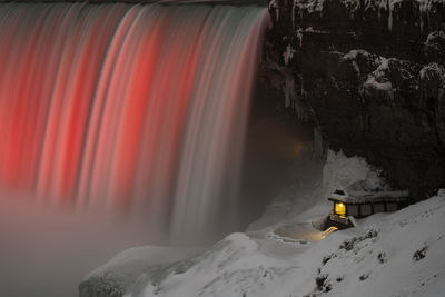 Horseshoe falls lit up in winter, also showing the journey behind the falls attraction.