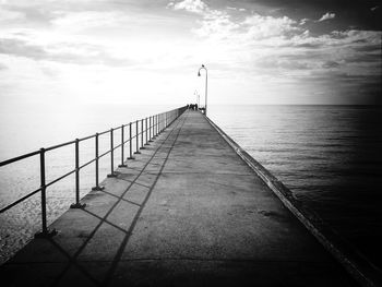 Jetty leading towards sea against sky