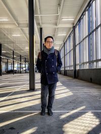 Full length portrait of young man standing in building