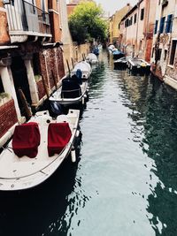 Boats moored in canal amidst buildings in city