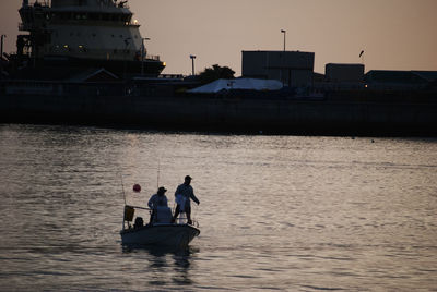 Men in boat fishing on sea against sky