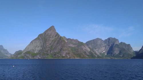 Scenic view of sea and mountains against blue sky