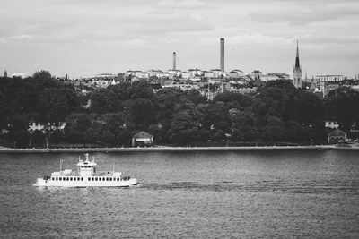 Boat on river by trees against sky