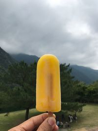 Person holding ice cream against mountains