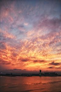 Scenic view of sea against dramatic sky during sunset