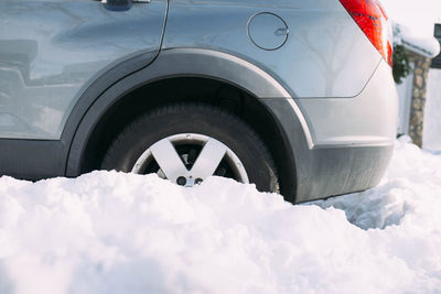 Car with wheel stuck in snow after heavy snowfall