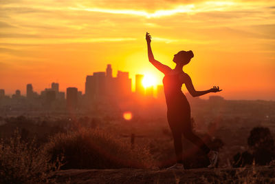 Silhouette man standing against orange sky