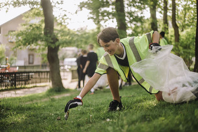 Smiling teenage boy collecting plastic in garbage bag