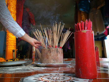 Midsection of person holding candles in temple against building
