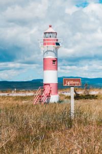 Information sign by lighthouse against sky