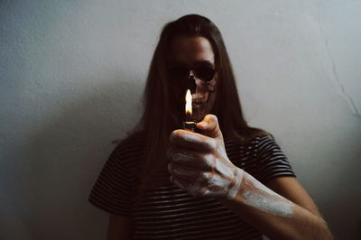 Portrait of woman with halloween make-up igniting cigarette lighter