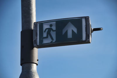 Low angle view of road sign against clear blue sky