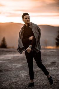 Full length of man standing on field against sky during sunset