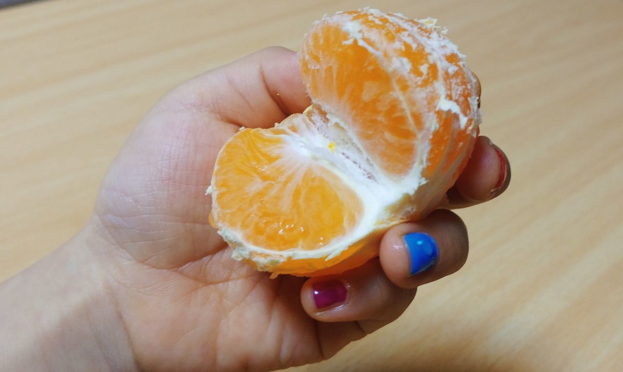 human hand, hand, one person, holding, human body part, food, food and drink, real people, unrecognizable person, freshness, close-up, body part, finger, lifestyles, indoors, human finger, orange color, focus on foreground, personal perspective, orange, temptation, snack