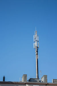 Low angle view of communications tower against blue sky