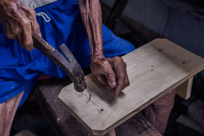 High angle view of man hammering nail on wood