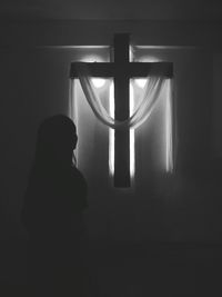 Rear view of woman looking through window at home