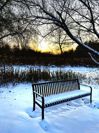 Empty bench on snow covered field during winter